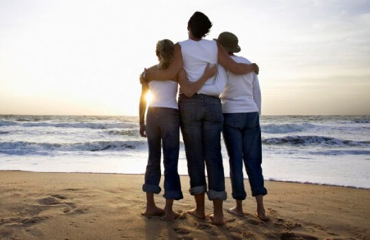 a family on a beach holding each other looking at the sunset