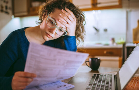 a woman worriedly looking at bills